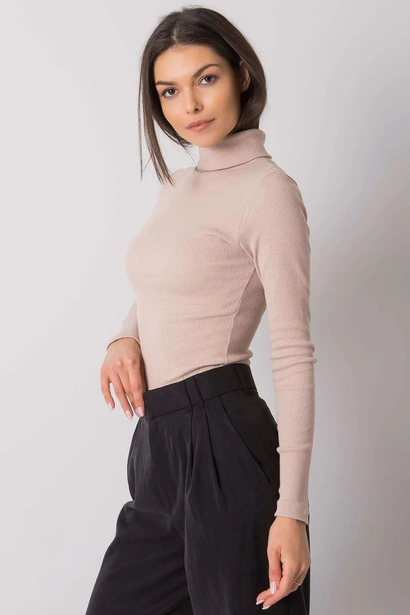 Fitted beige ribbed turtleneck top with long sleeves worn by a model.