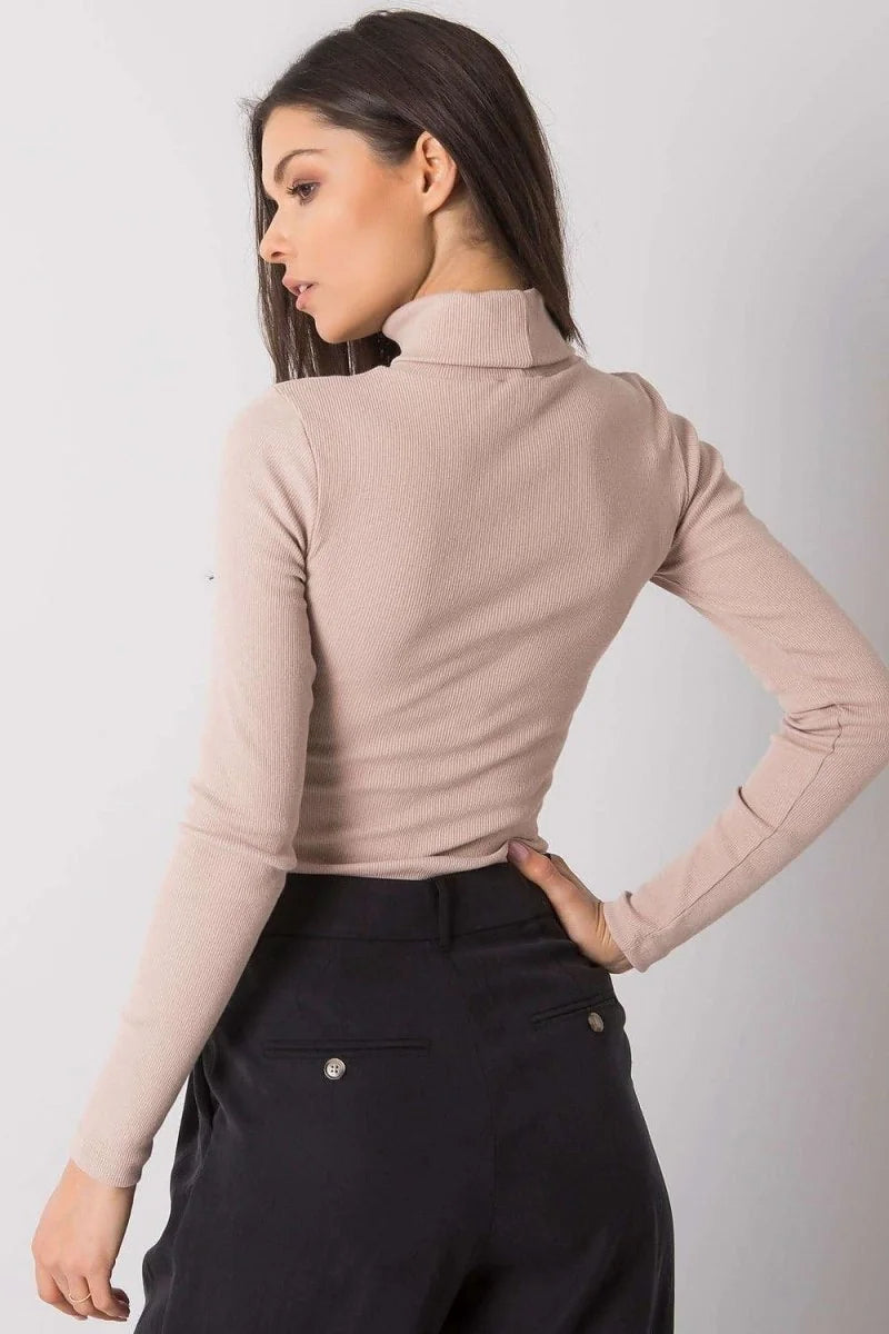 Fitted beige ribbed turtleneck top with long sleeves, shown on a model wearing black pants.
