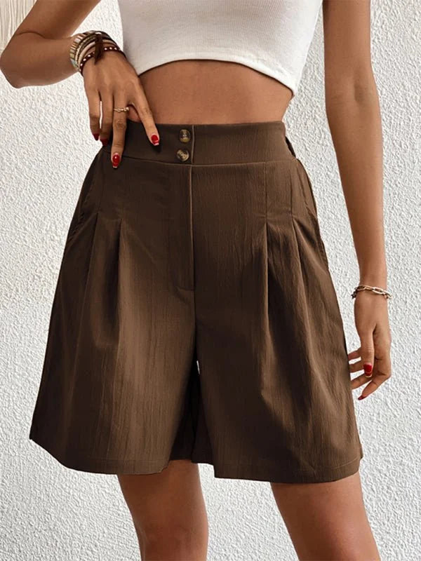Brown pleated shorts with a high waist and button closure, shown on a model.