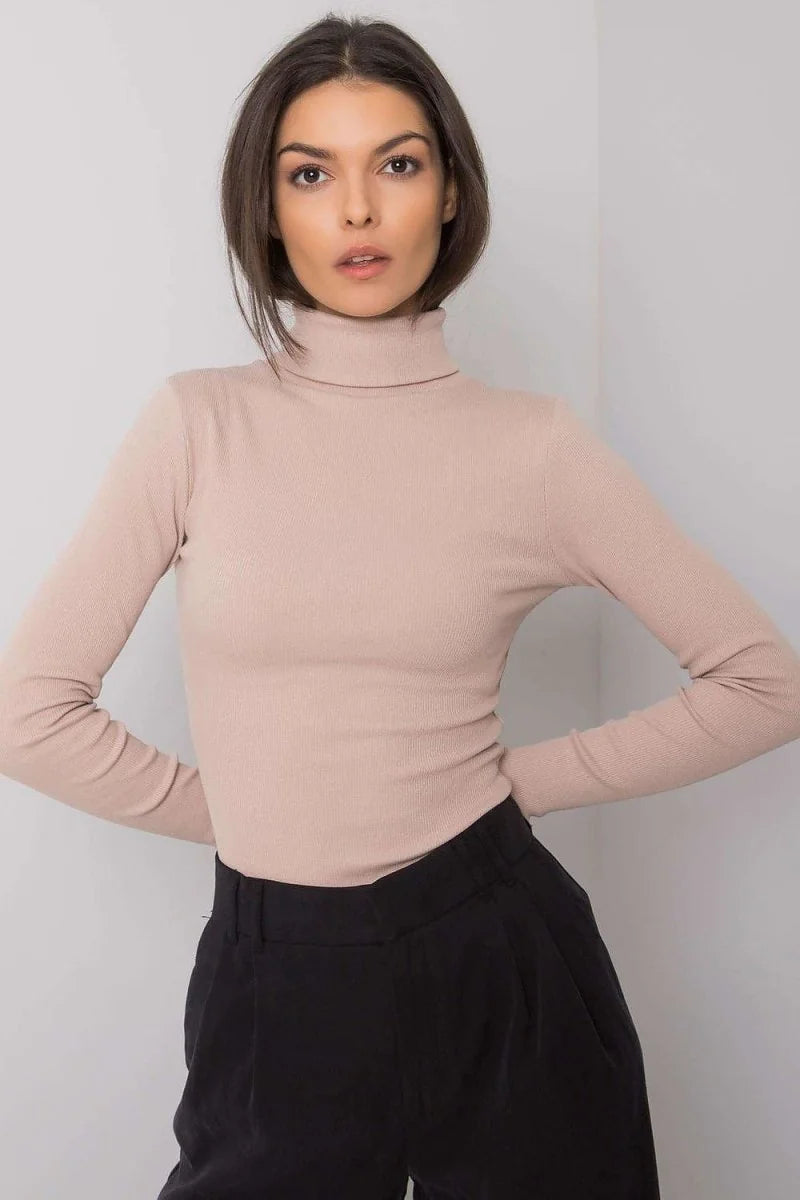 Fitted beige ribbed turtleneck with long sleeves, worn with black pants.