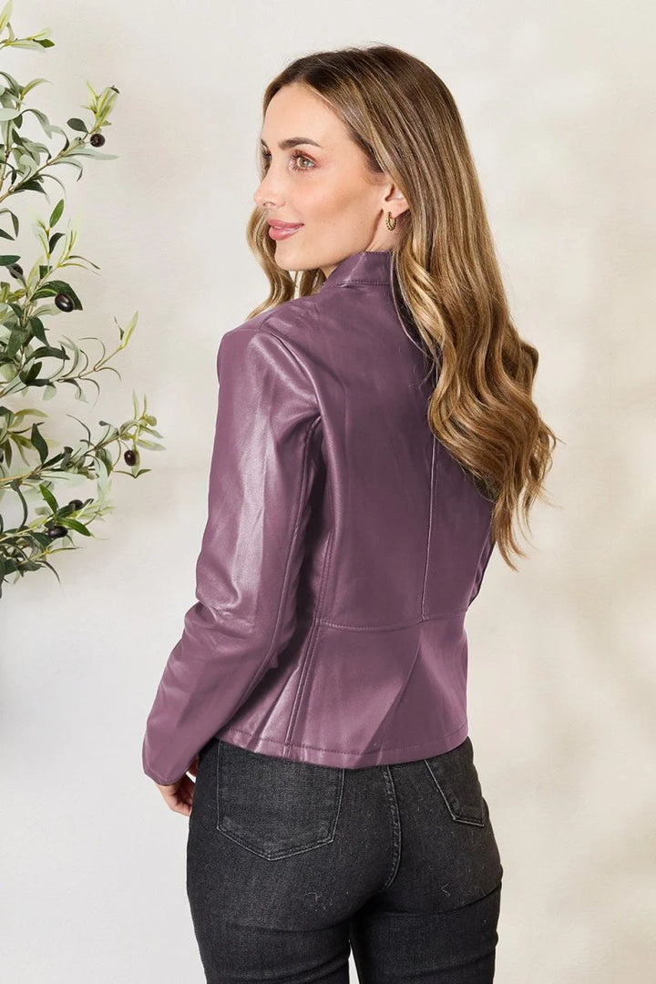 Woman wearing a plum faux leather jacket and dark wash jeans.