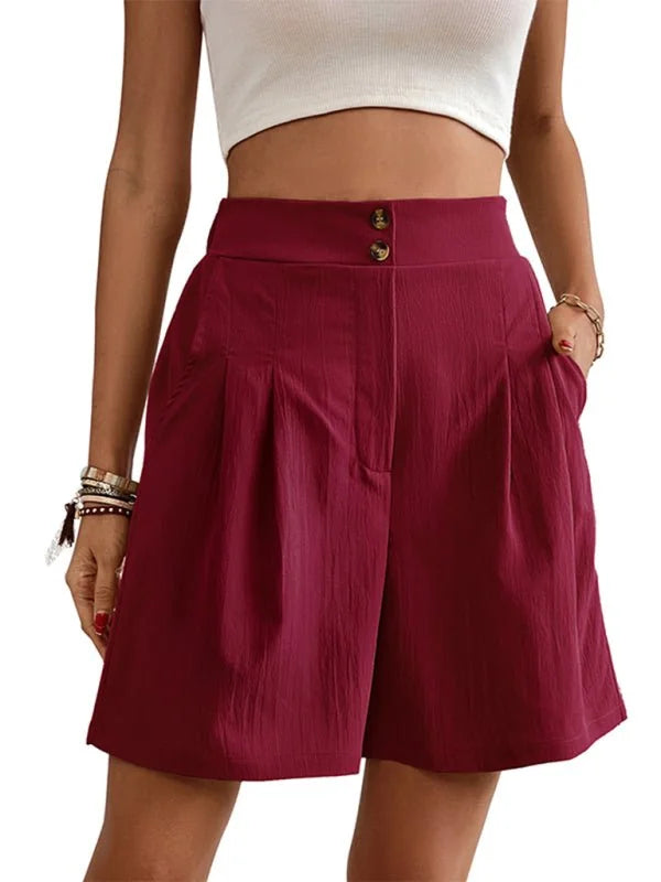 Burgundy pleated shorts with double button closure and pocket detail, shown on model.