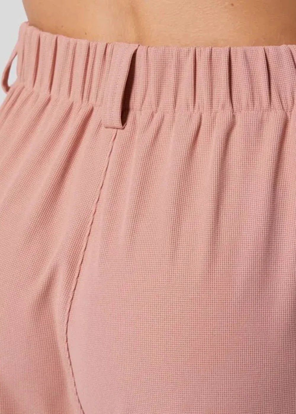 Close-up of pink waffle-knit pants with an elastic waistband and front seam detail.