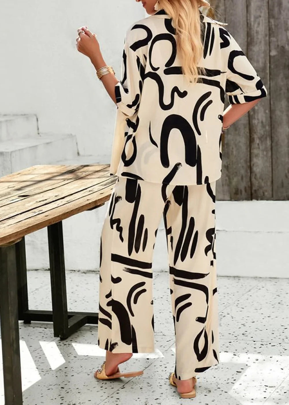 Champagne-colored pant suit with a black abstract print, wide-leg pants, and a relaxed fit, shown on a model.