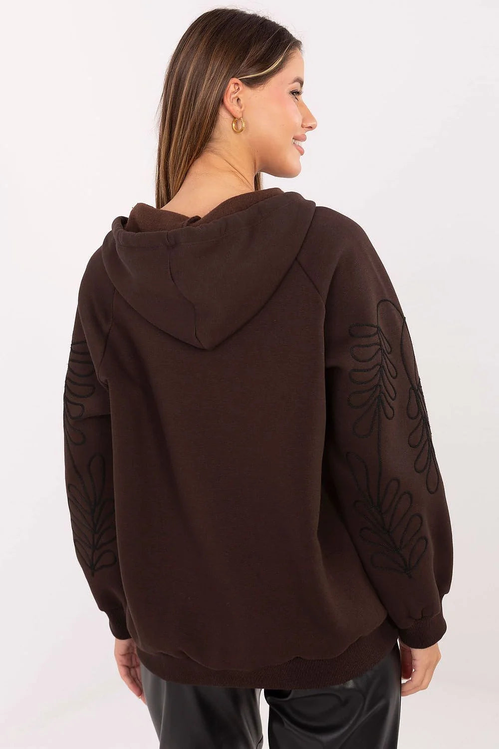 Brown hooded sweatshirt with embroidered leaf pattern on sleeves, on a model.