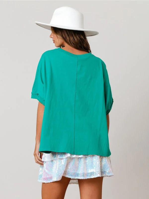 Back view of a woman wearing a bright teal top and a sequined skirt.