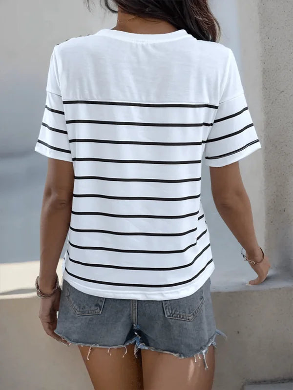 Woman wearing a white t-shirt with horizontal black stripes and denim shorts.