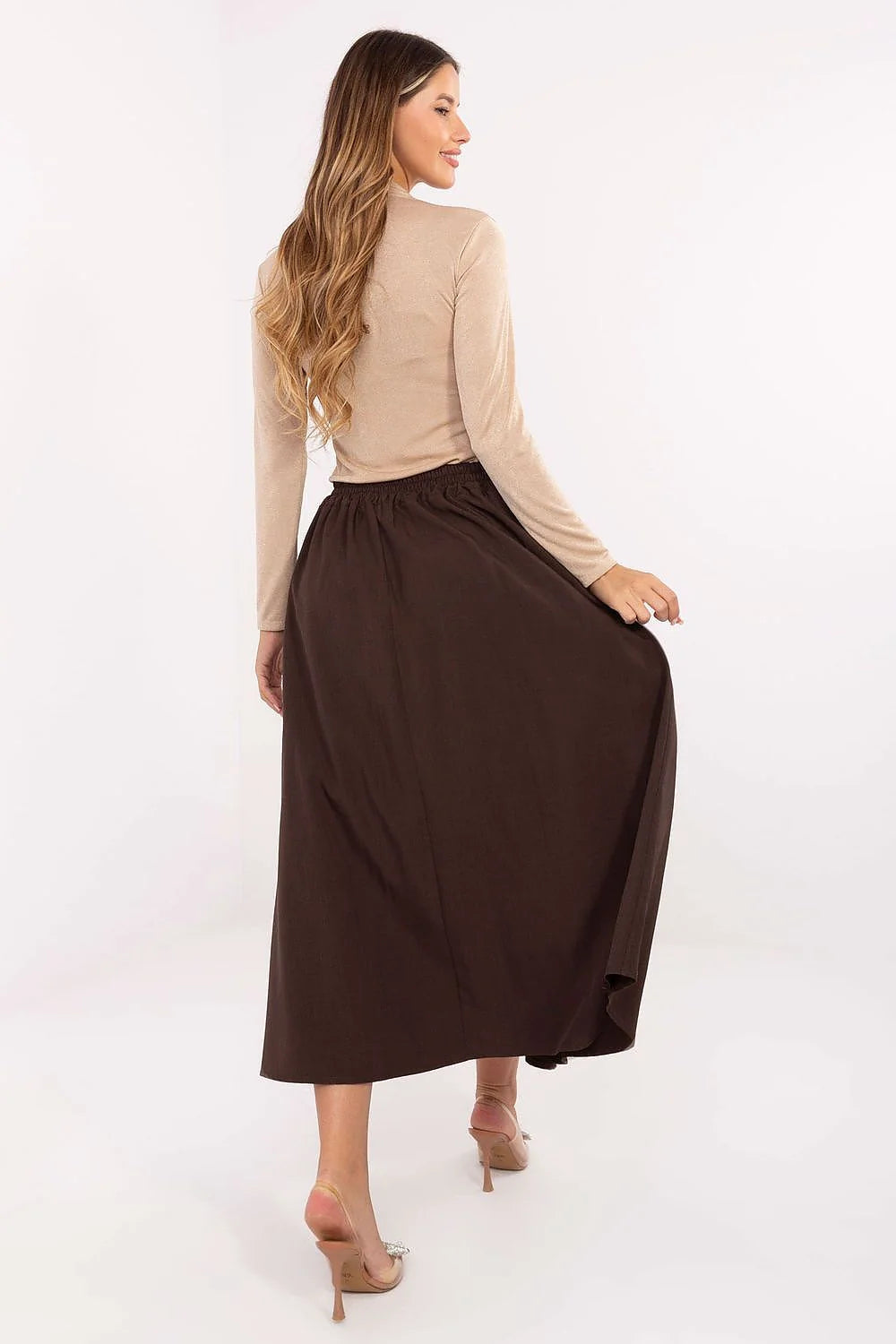 Woman from behind wearing a brown maxi skirt and a beige long-sleeve top.