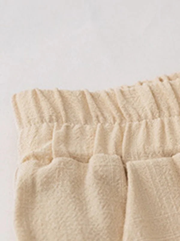 Close-up of a cream-colored linen-blend fabric with a textured weave and elastic waistband.