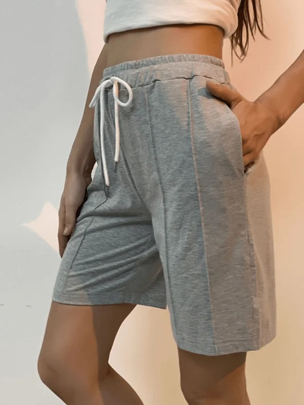 Grey sweat shorts with drawstring waist and pockets, on model.