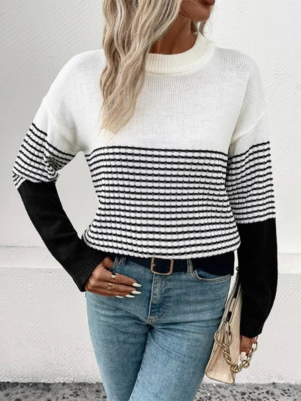 White and black striped knit sweater with solid black sleeves, worn by a model with blue jeans.
