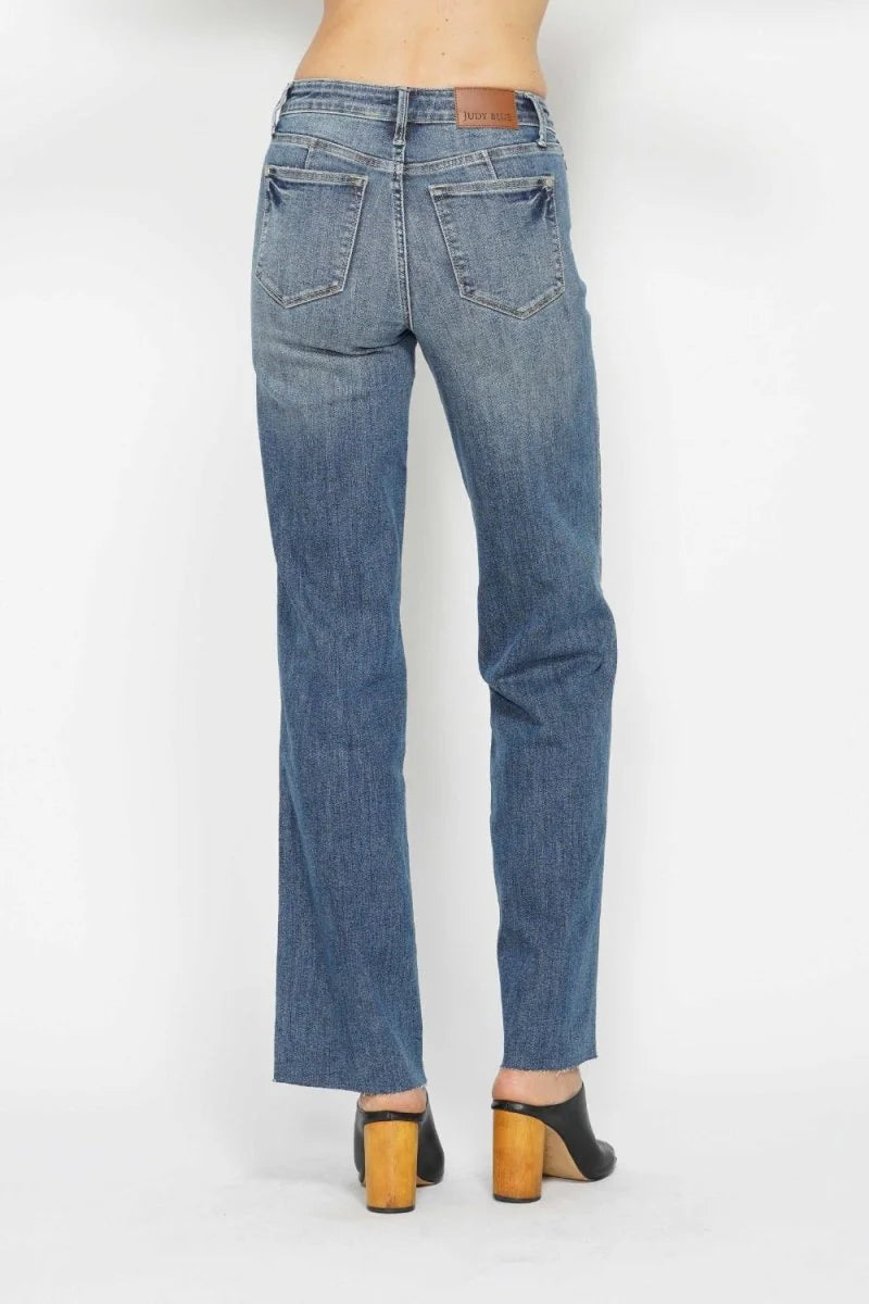 Back view of straight-leg jeans with a frayed hem and a brown leather patch at the waistband.