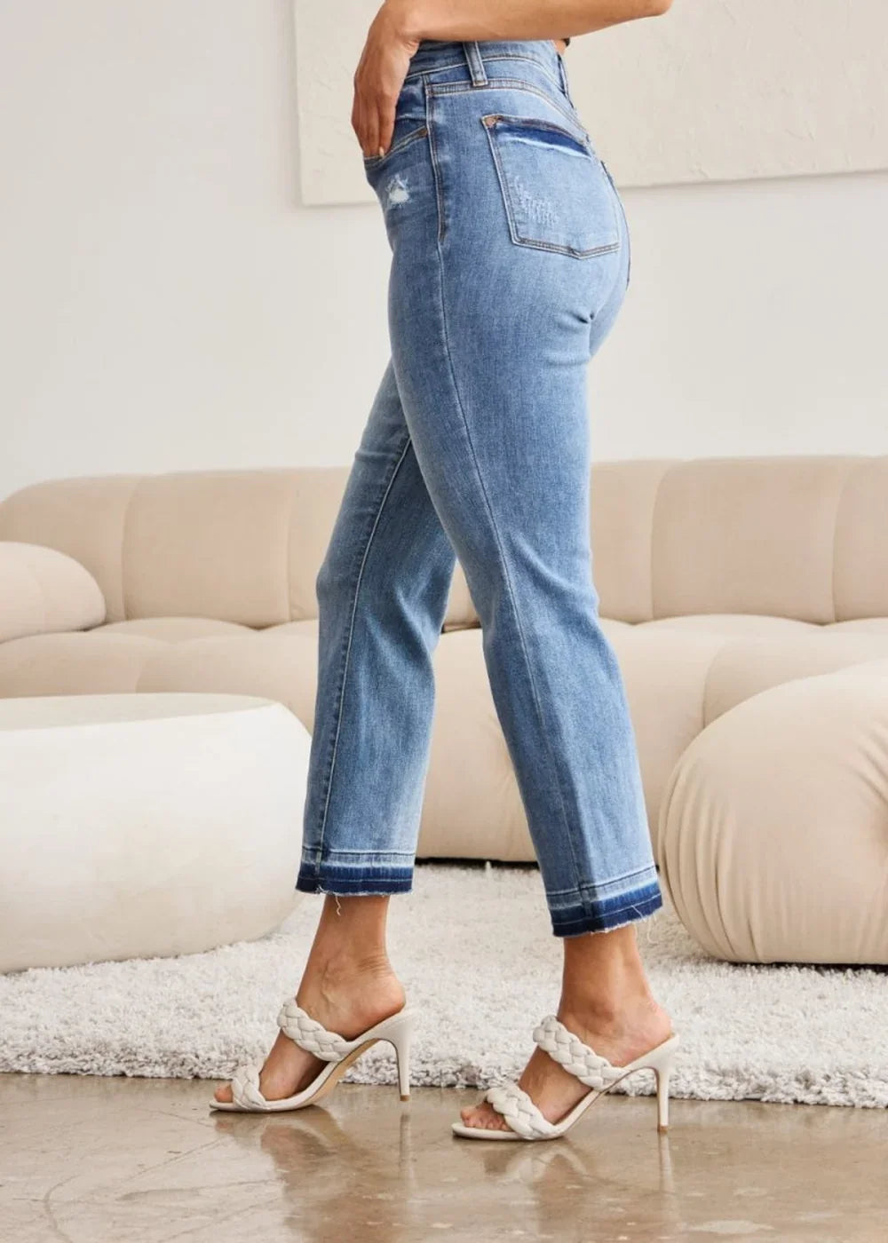 Light wash denim jeans with frayed hem and distressed details, shown on a model.