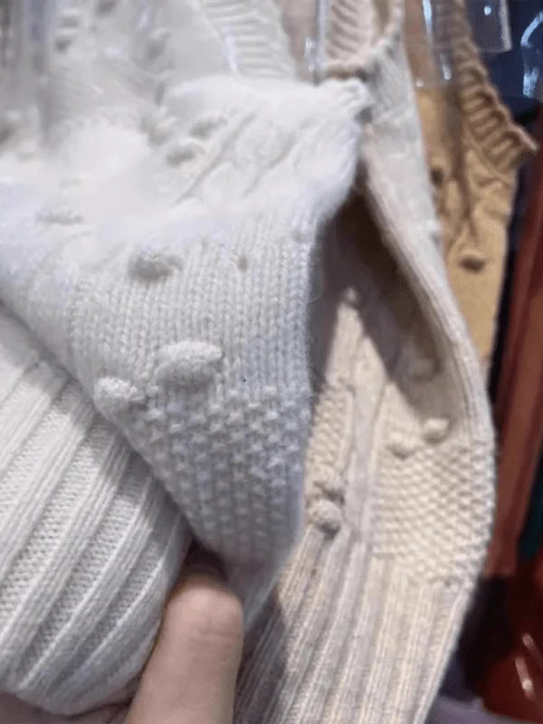 Model wearing a cream knit vest over a white top