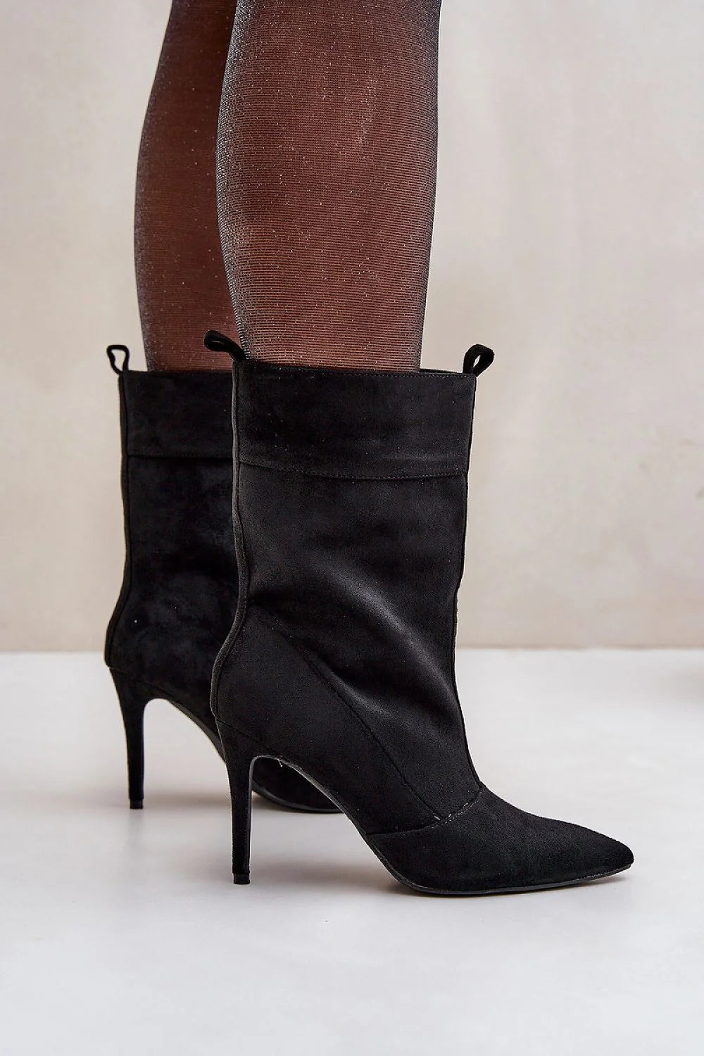Black suede pointed-toe heeled ankle boots with glittery brown tights.