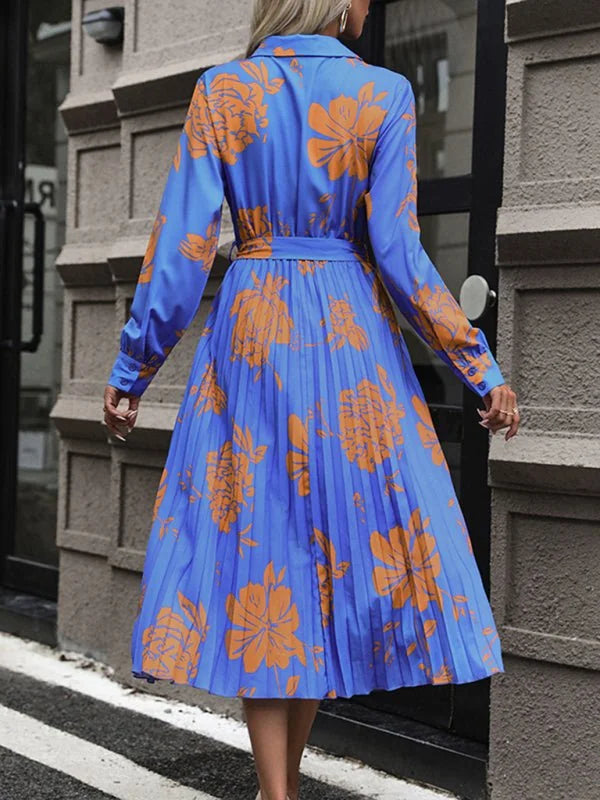 Blue pleated midi dress with an orange floral print and a belted waist, shown from the back.