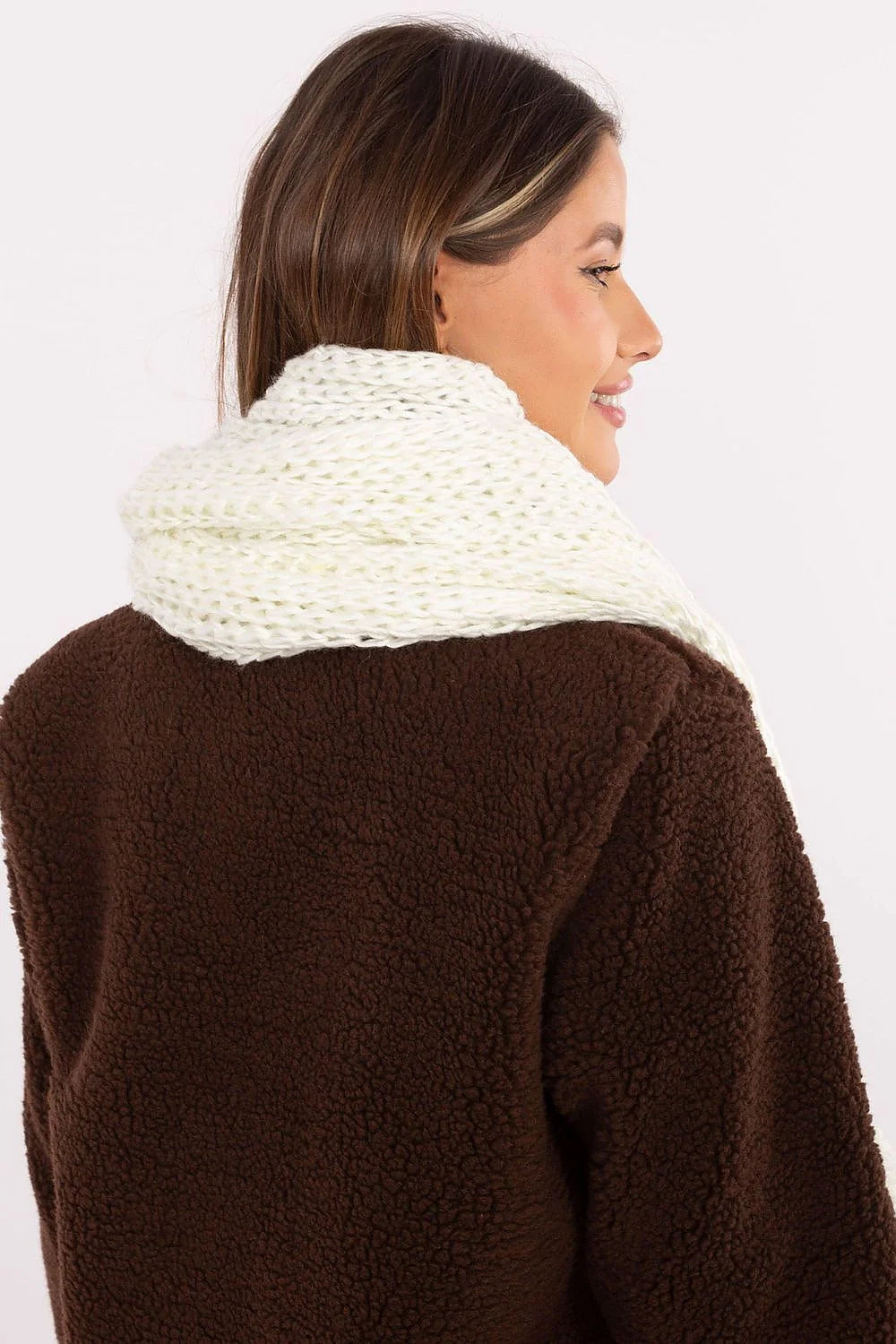 Close-up of a woman wearing a fluffy brown jacket and a cream knitted scarf.