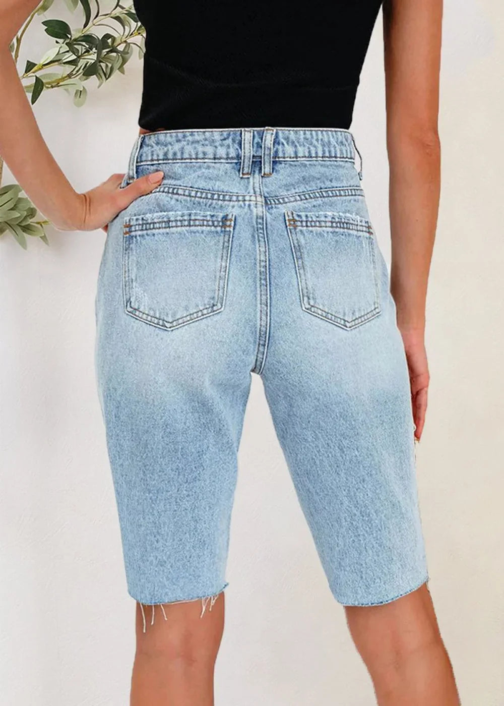 Model wearing light wash distressed denim shorts