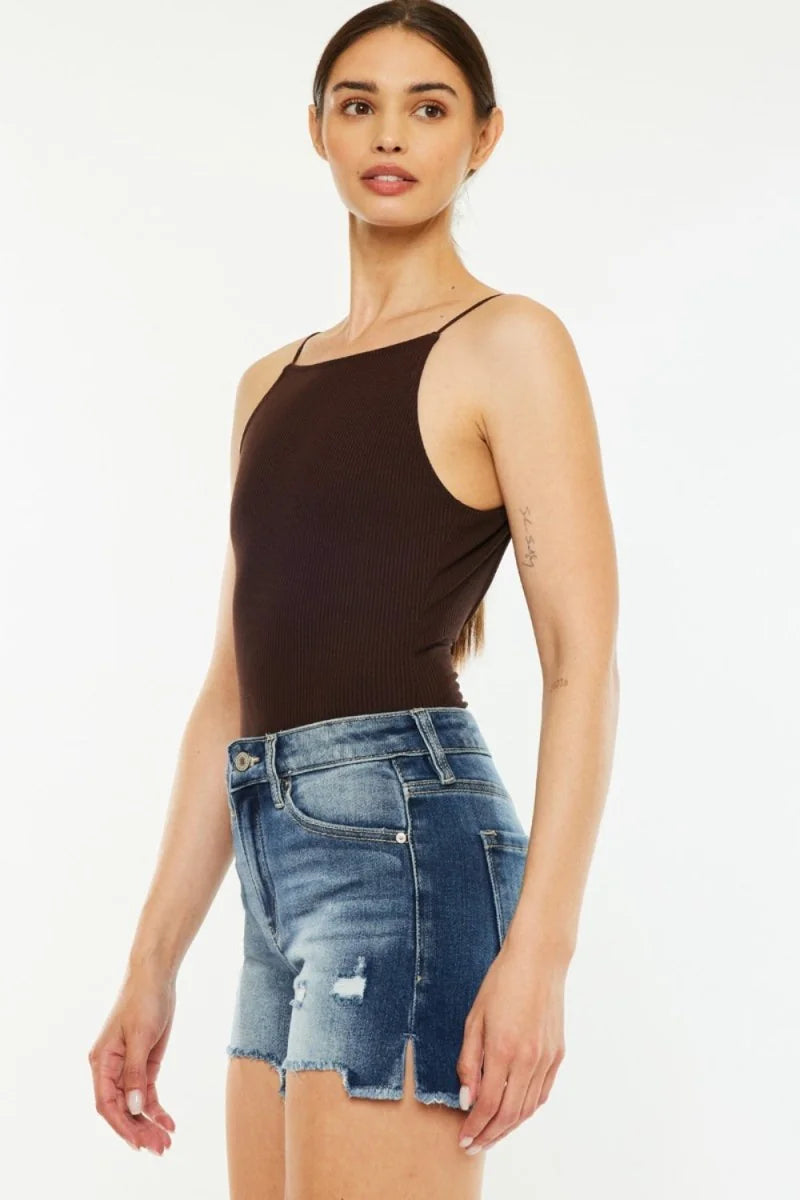 Distressed denim shorts with frayed, split hem and a dark brown ribbed tank top on a model.