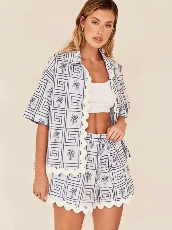 Blue and white palm tree and geometric print pajama set with scalloped trim on model.