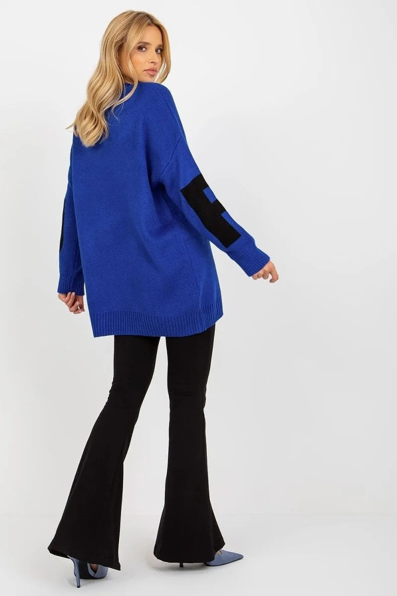 Royal blue knit sweater with black geometric details on sleeves, worn with black bell-bottom pants.