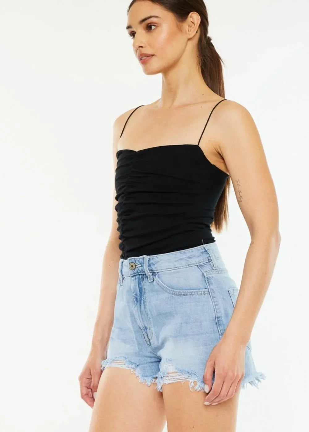 Light wash distressed denim shorts with frayed hem on a model.