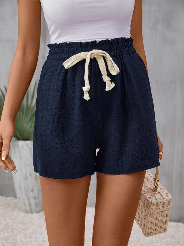 Navy blue textured shorts with a drawstring waist and ruffled hem, shown on model.