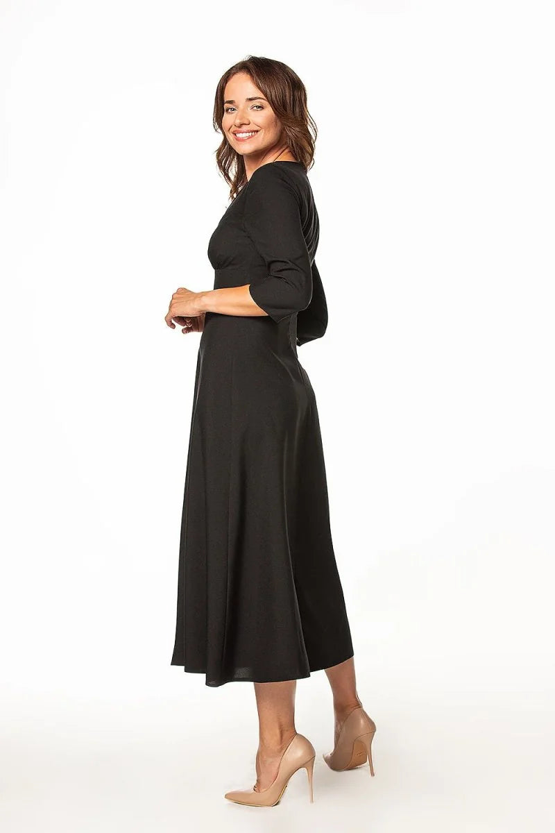 Black midi dress with 3/4 sleeves and a flared skirt, worn with nude heels.