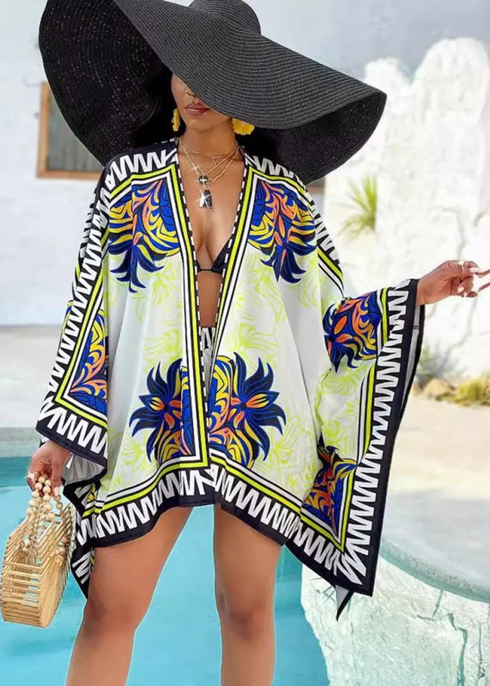 Woman in a wide-brimmed black hat and a white kimono with a vibrant blue, yellow, and orange floral print.