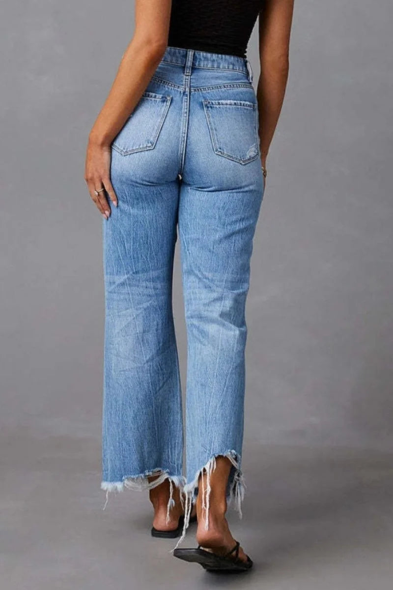 Light wash distressed denim jeans with frayed hem, shown from the back on a model.