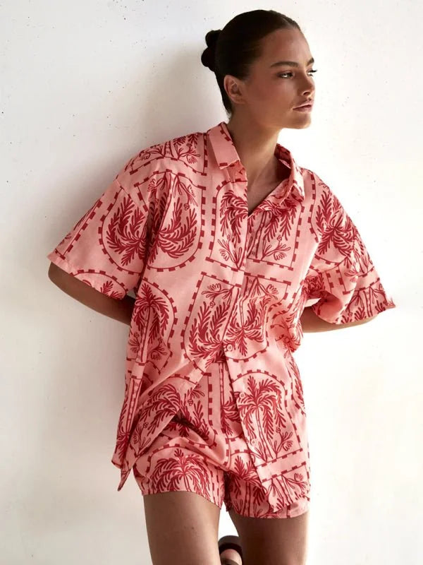 Coral short suit with a red palm tree print, relaxed fit, on a model.