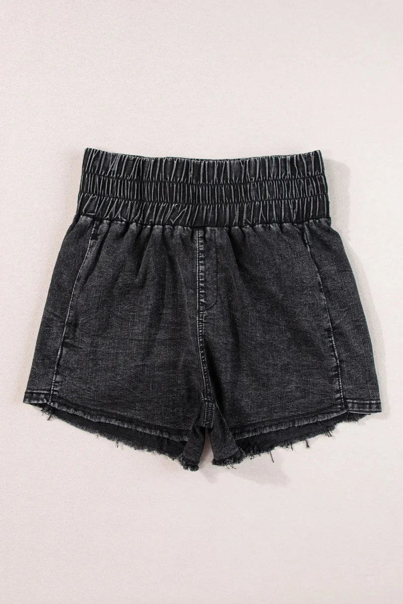 Distressed black denim shorts with a high-waisted elastic smocked waistband and frayed hem.