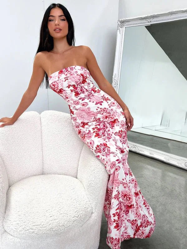 Strapless maxi dress with a vibrant pink and red floral pattern on a white background, fitted to the body with a flared hem.