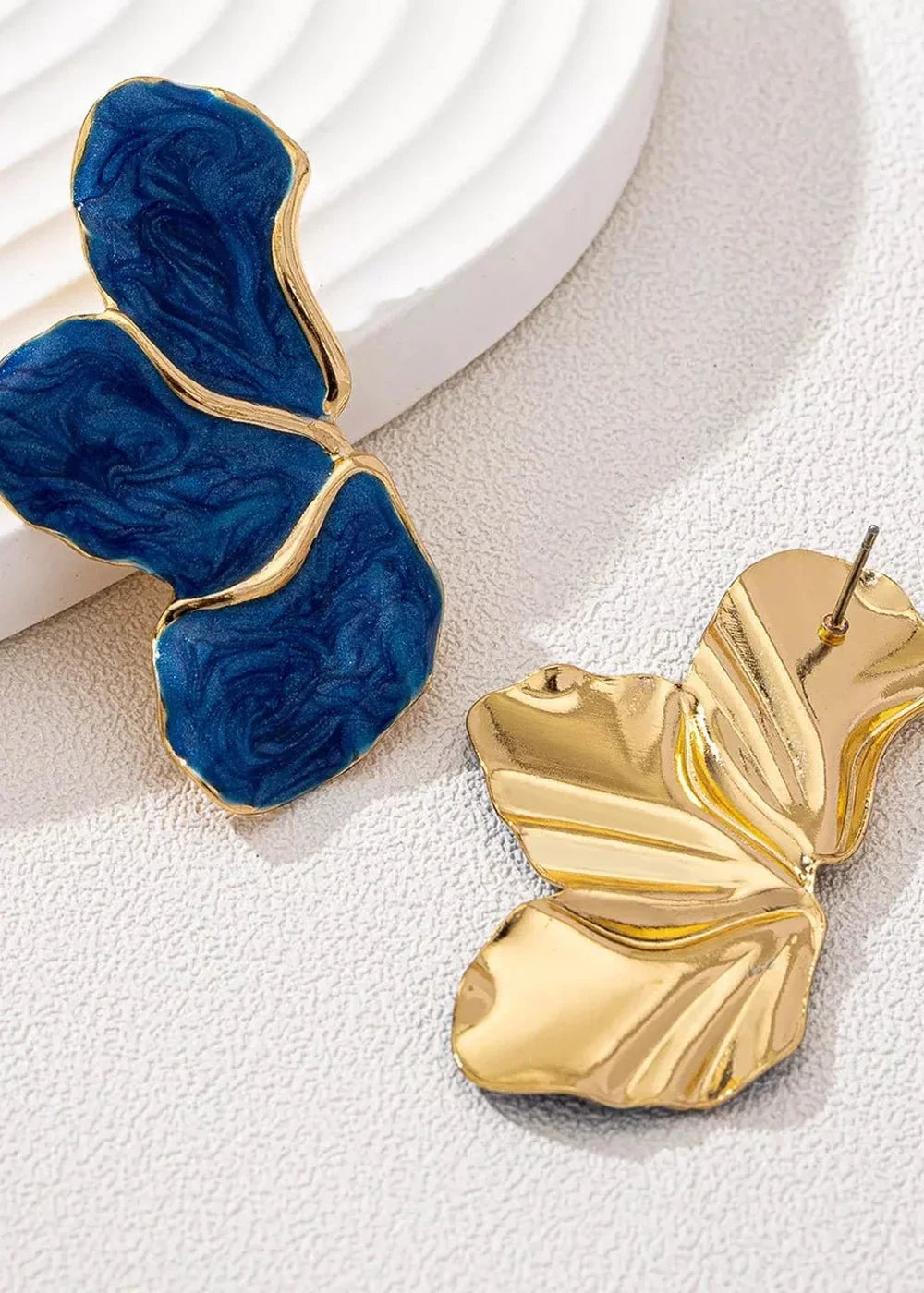 Gold-plated and blue resin petal-shaped earrings with a marbled pattern.