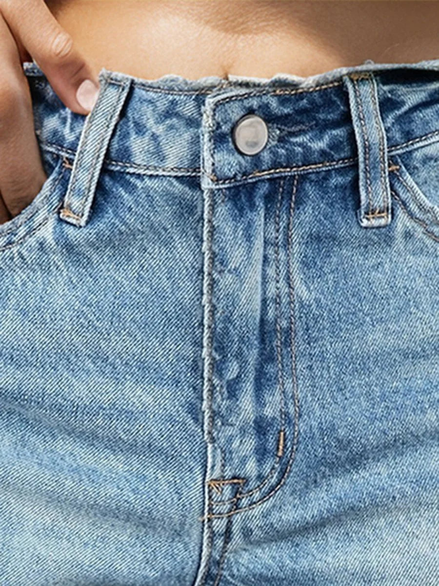 Close-up of light blue distressed denim shorts with a button closure and frayed hem.