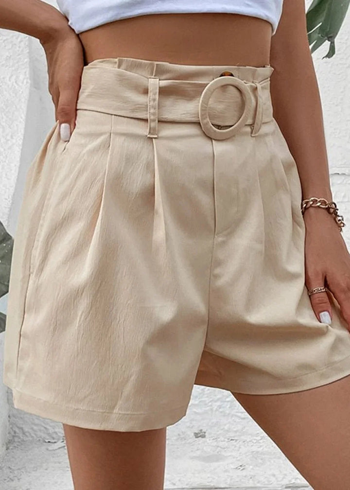 Light beige paperbag waist shorts with a belt and circular buckle detail, on model.