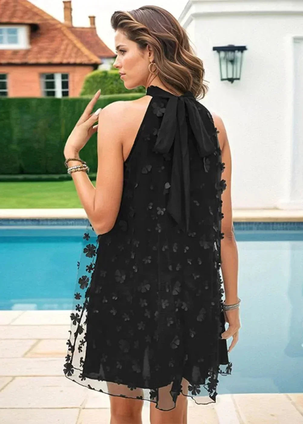 Black floral appliqué halter dress with a bow tie back and sheer hem.