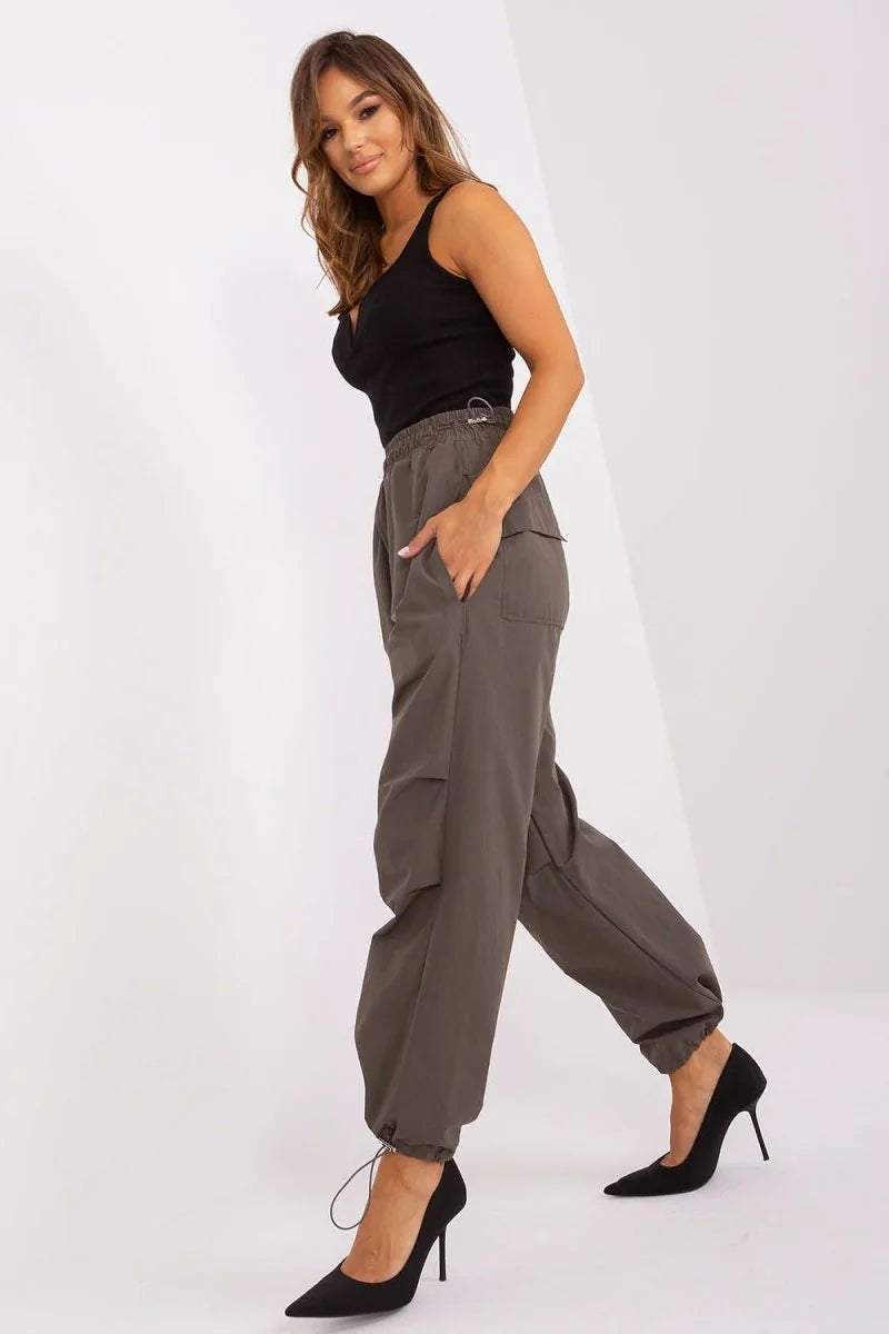 Woman in a black tank top and olive green cargo pants with cinched ankles and black heels.