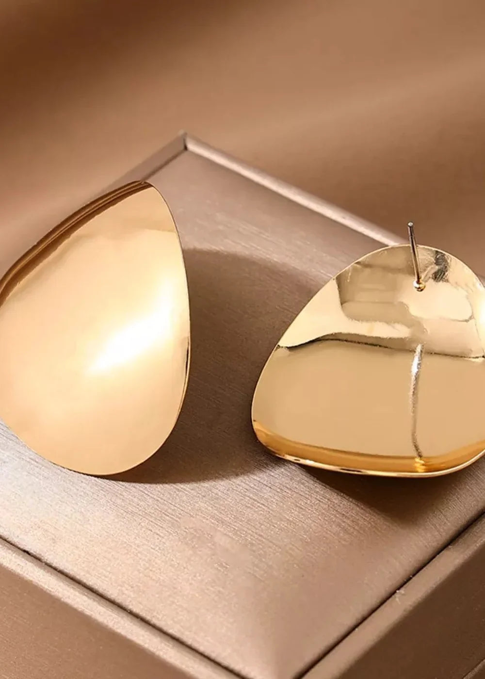 Shiny golden teardrop earrings with a polished metallic finish.