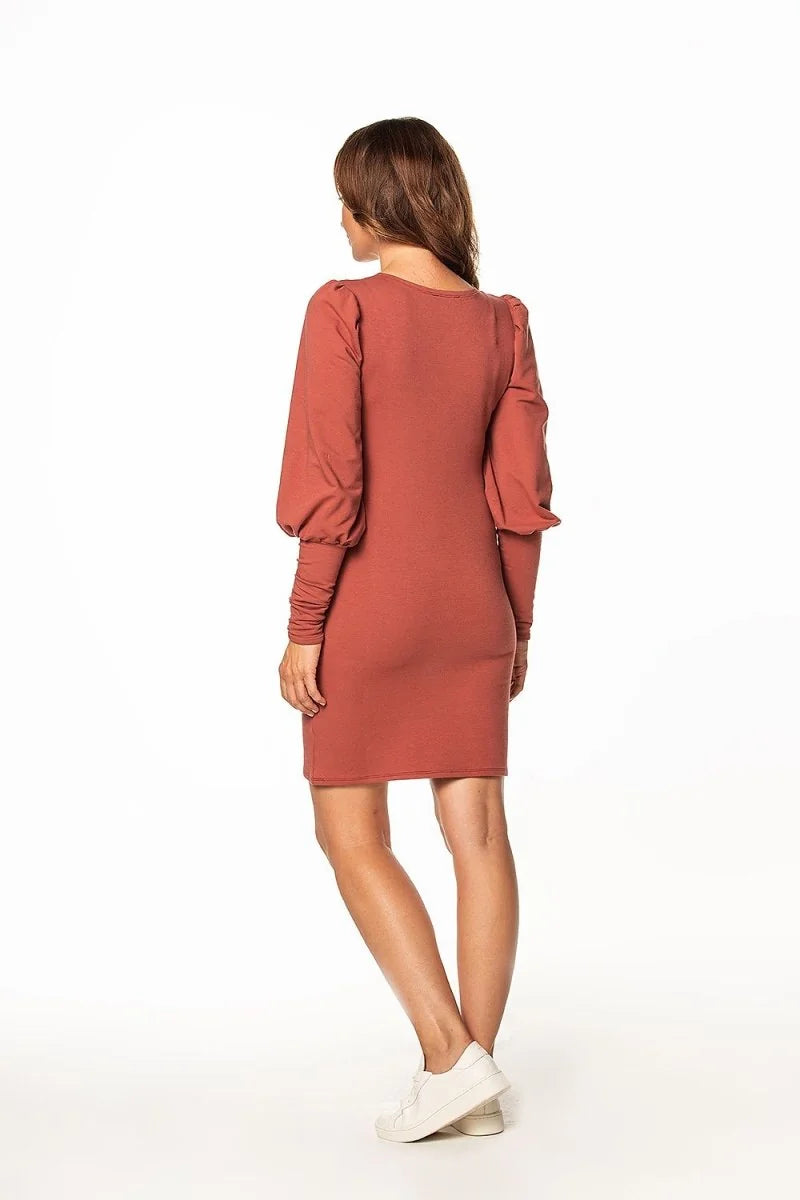 Terracotta long-sleeve knit dress with puffed sleeves and white sneakers.
