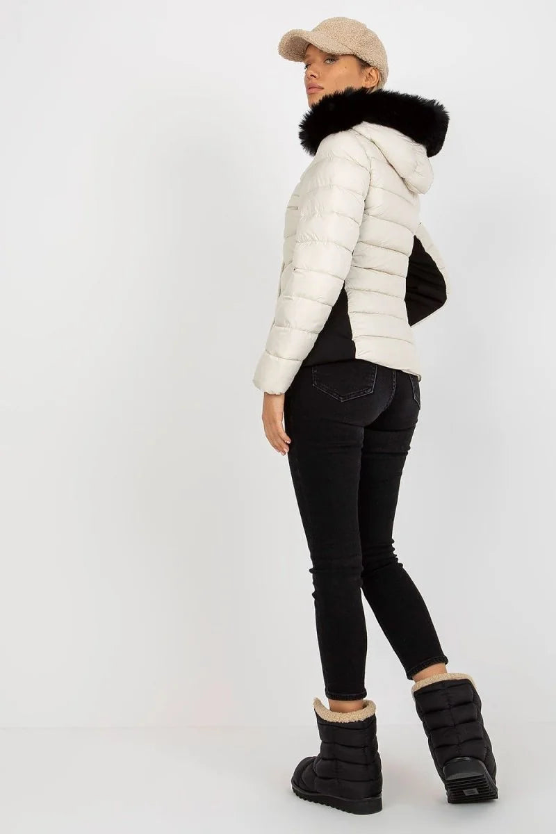 Cream puffer jacket with black fur trim, black jeans, and black puffer boots on a model.