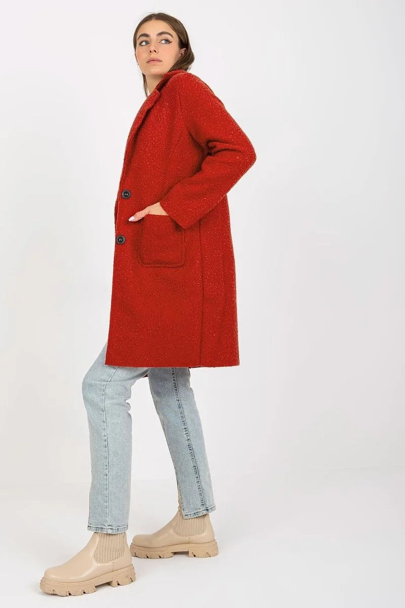 Red textured coat with black buttons and light blue jeans on a model.