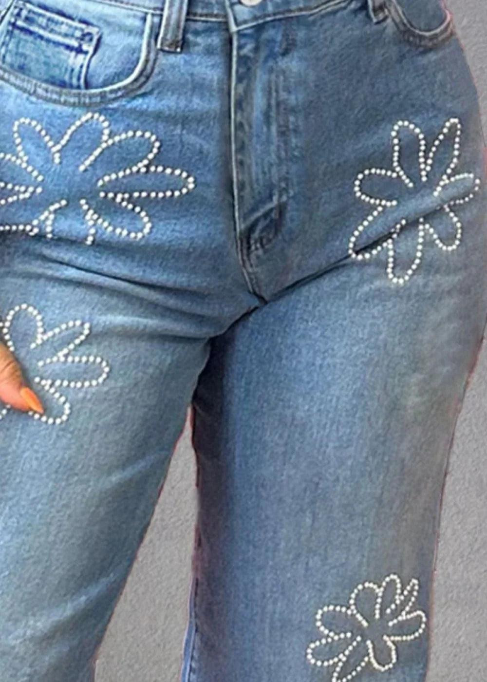 Light wash denim jeans with scattered pearl flower embellishments.