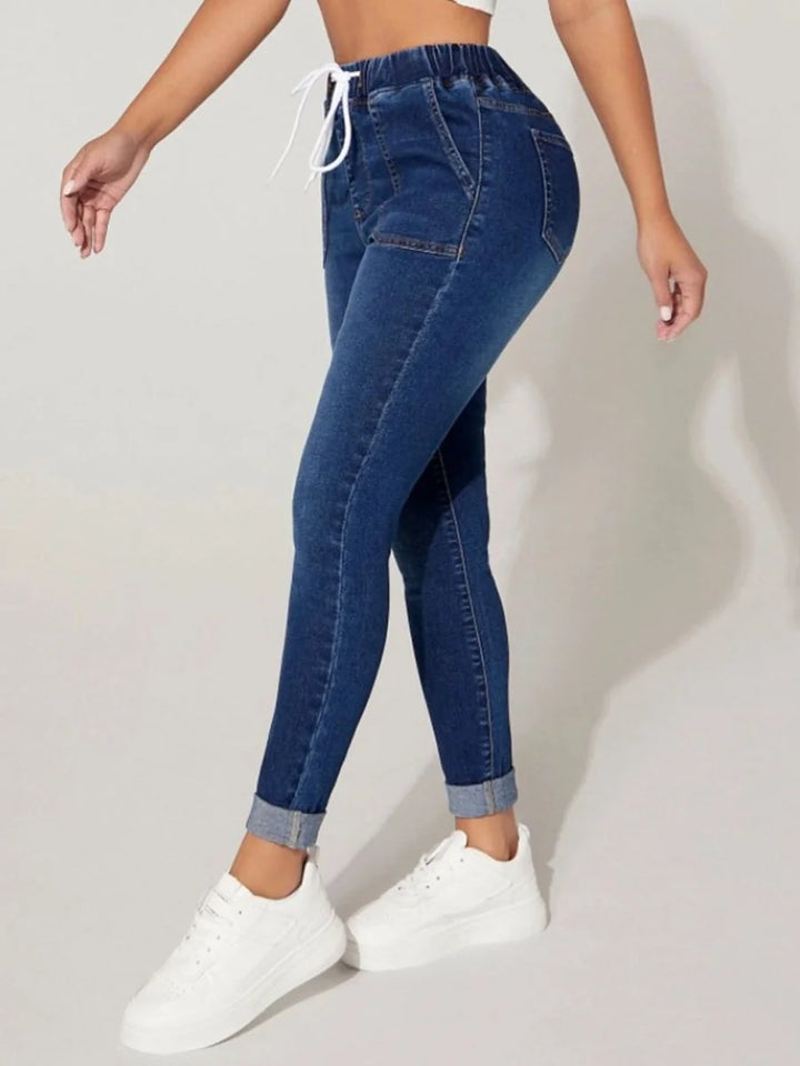 Medium wash denim joggers with a drawstring waist and cuffed hems.