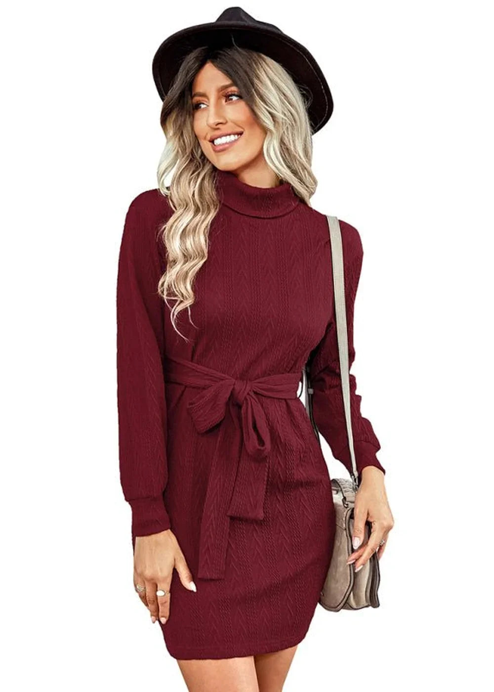 Burgundy knit turtleneck dress with a tie waist and a textured pattern, worn by a model with a black hat.