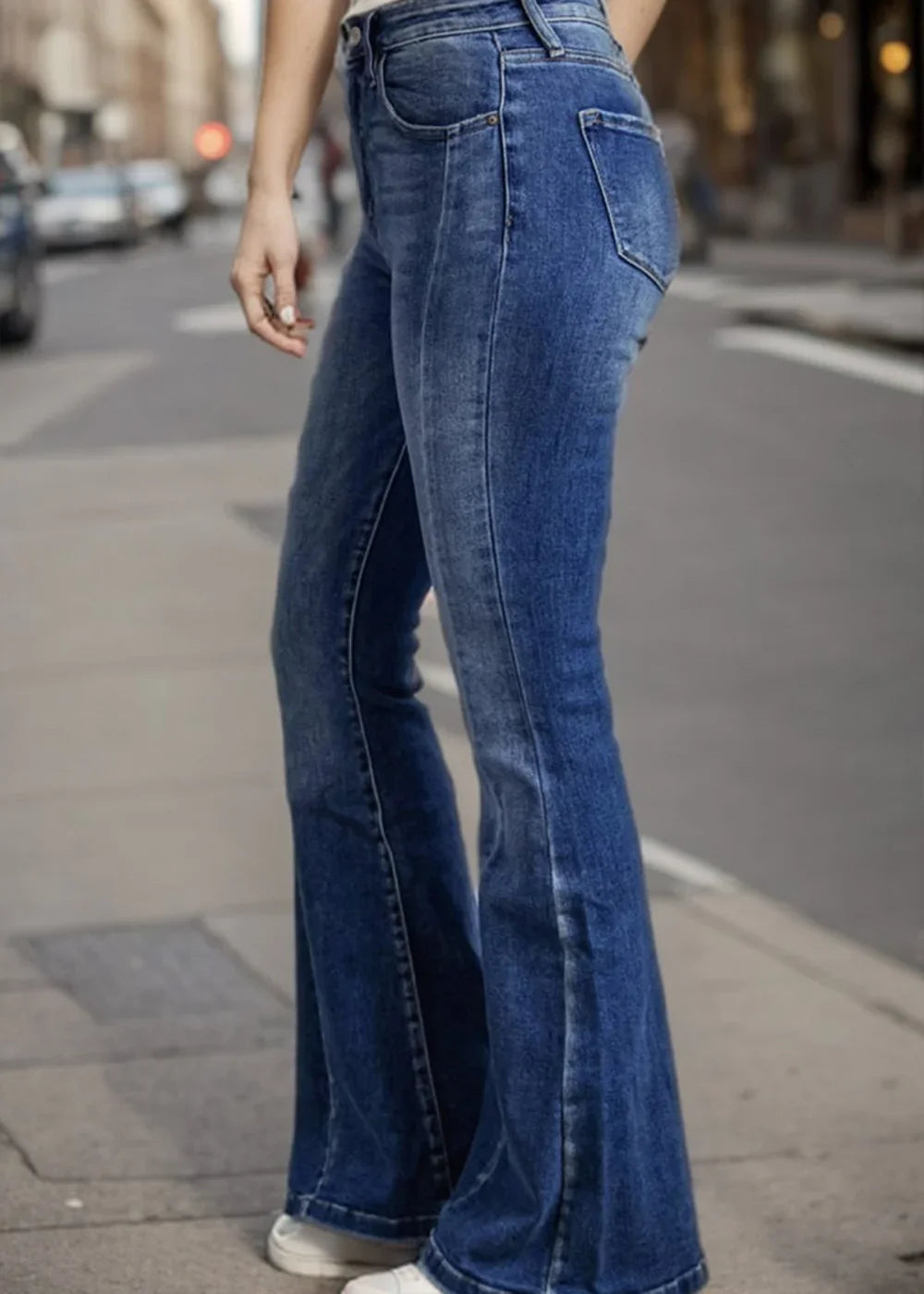Close-up of medium-wash flared jeans with a faded texture and visible stitching detail.