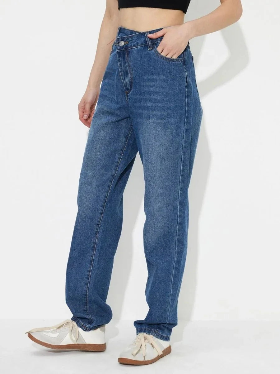 Medium blue denim jeans with a unique crossover waist and white sneakers.