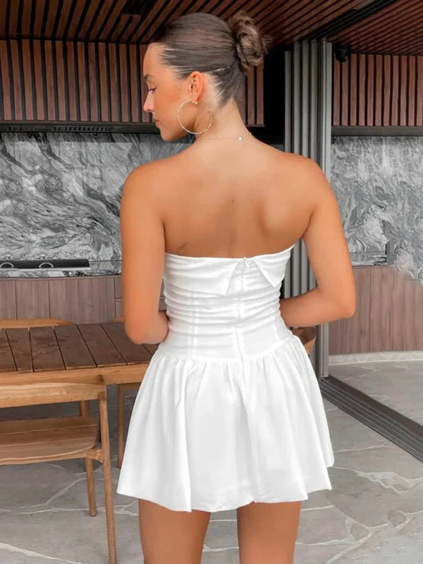 White strapless mini dress with ruched bodice and flared skirt, shown from the back on a model.