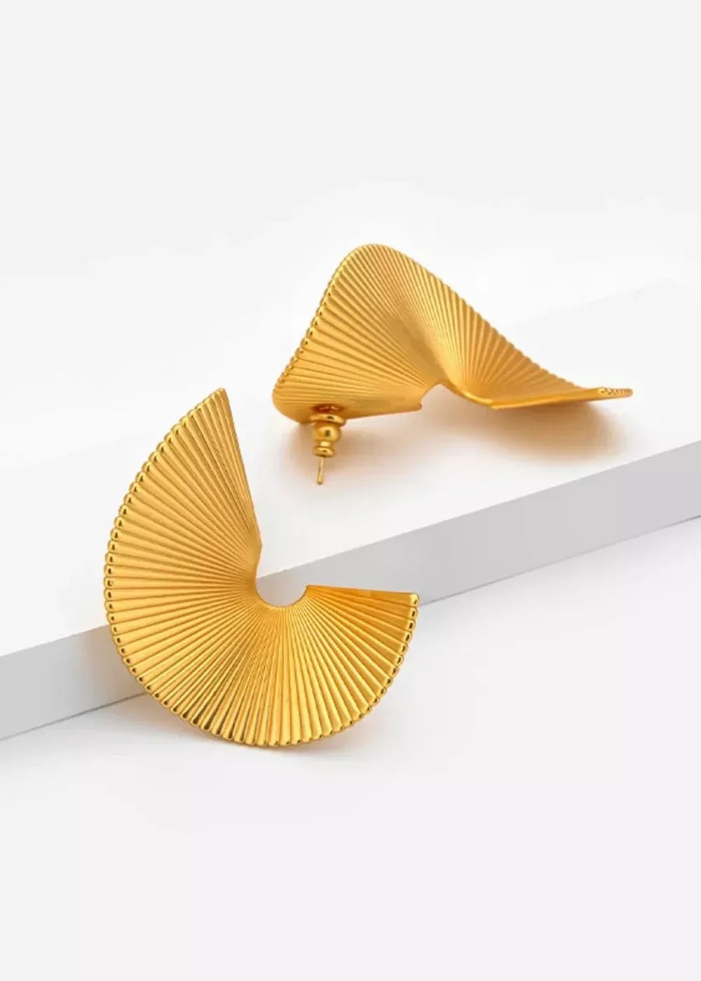 Gold fan-shaped earrings with ribbed texture on a white surface.
