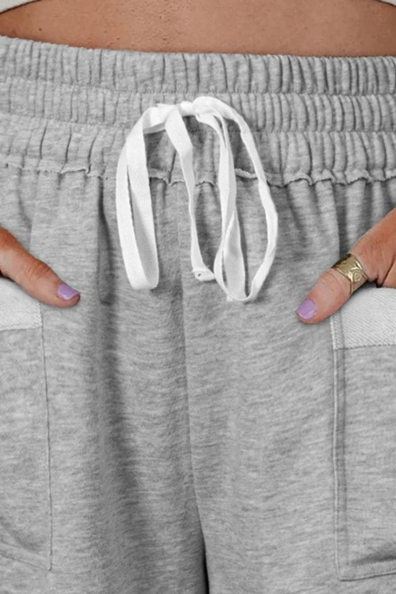 Close-up of grey heathered drawstring sweatshorts with white drawstring and pockets.